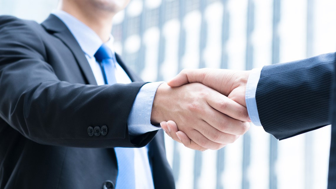 Two professionals shaking hands in a modern business setting